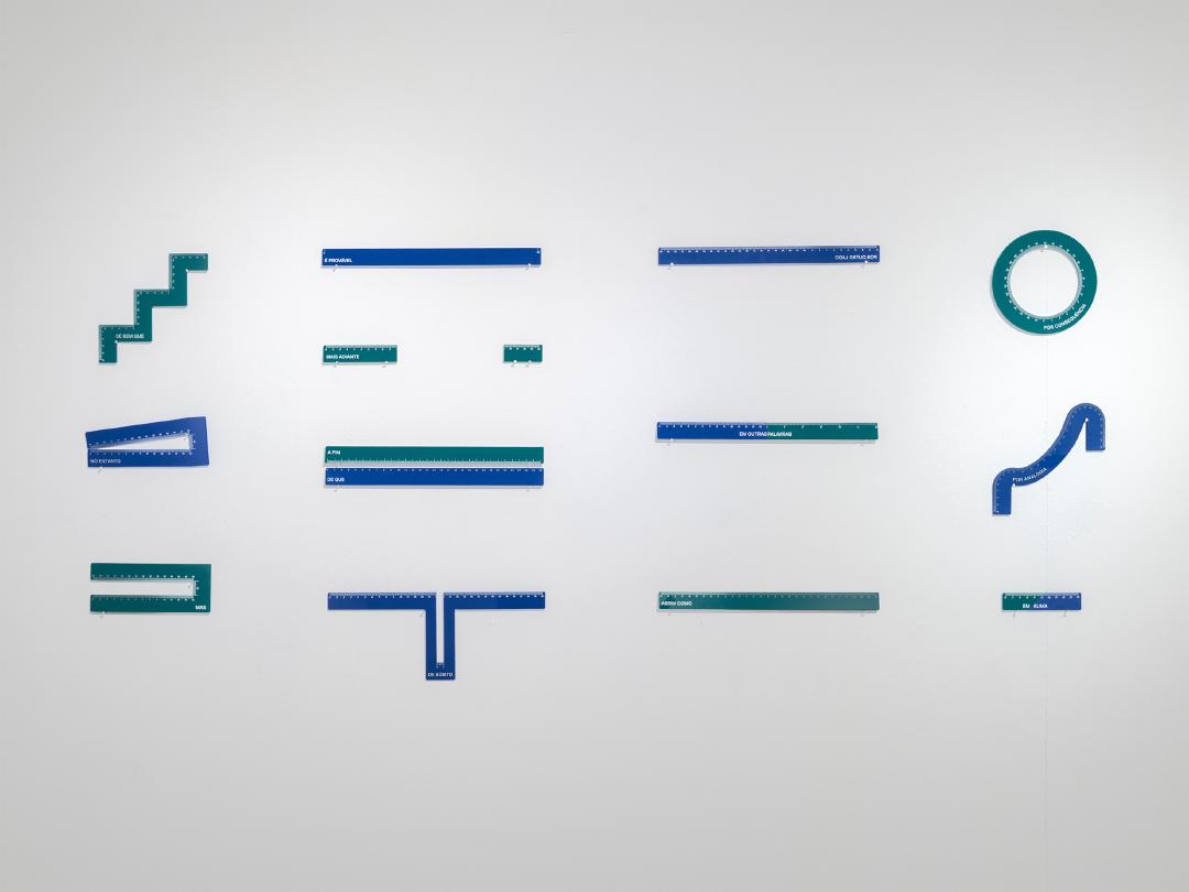 Conjunto de 13 réguas de acrílico em diferentes formatos penduradas em uma parede branca